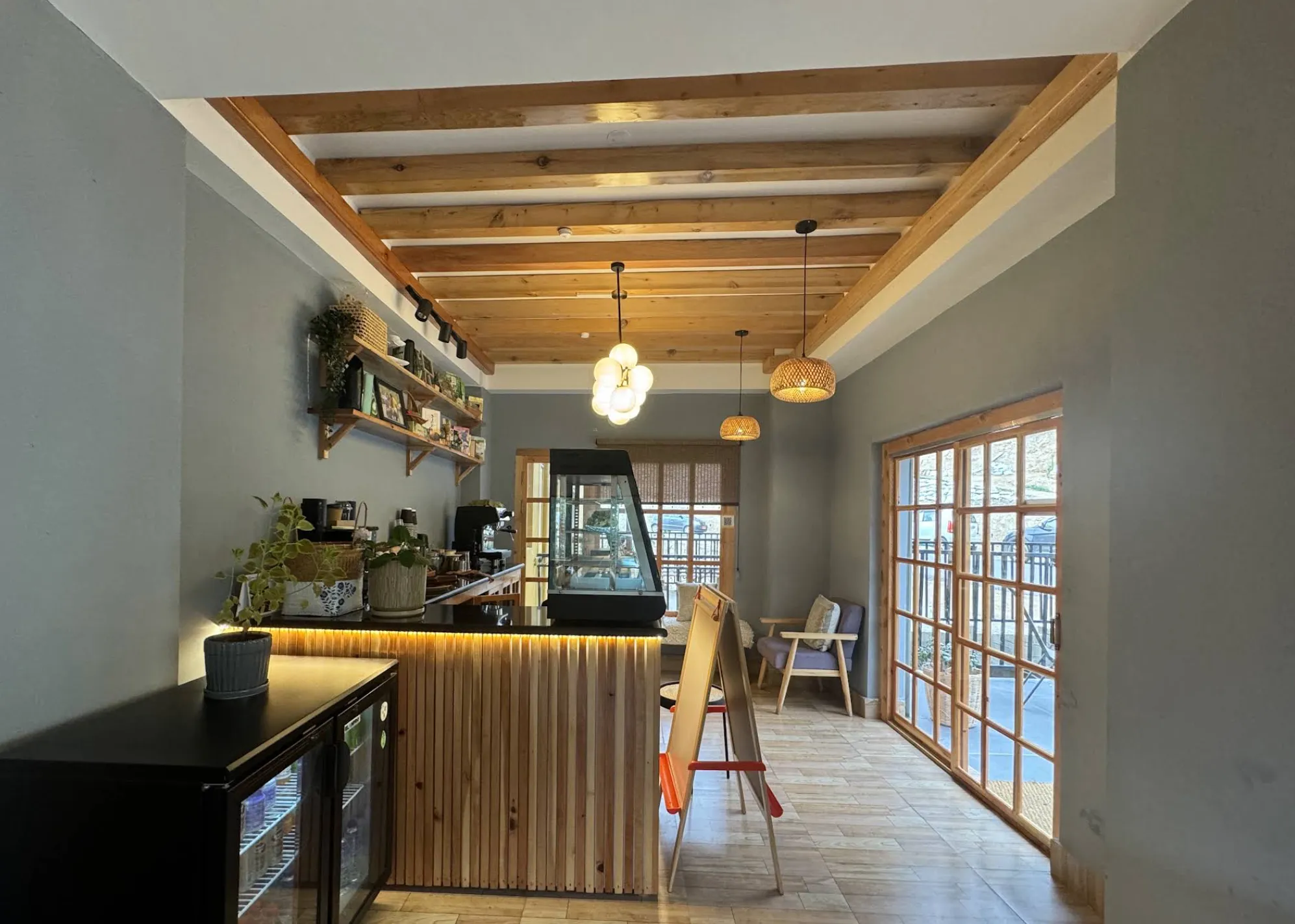 Inside the café: wooden counter, beamed ceiling, pendant lights and glass doors to the patio